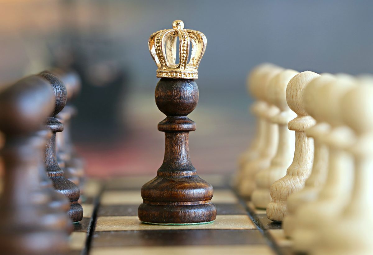 Chess king piece surrounded by pawns on a chessboard