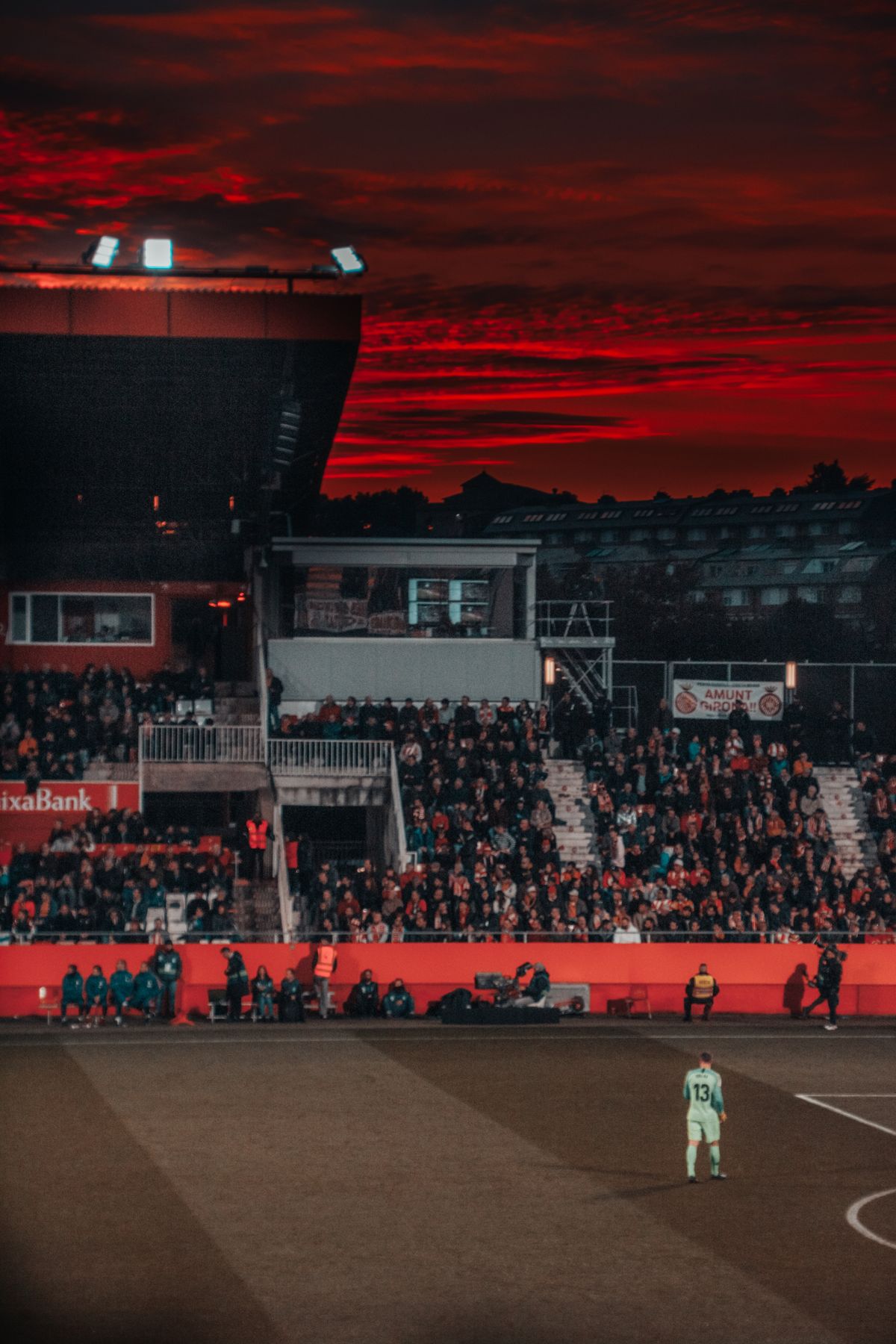 Footballer facing a packed stadium crowd at sunset