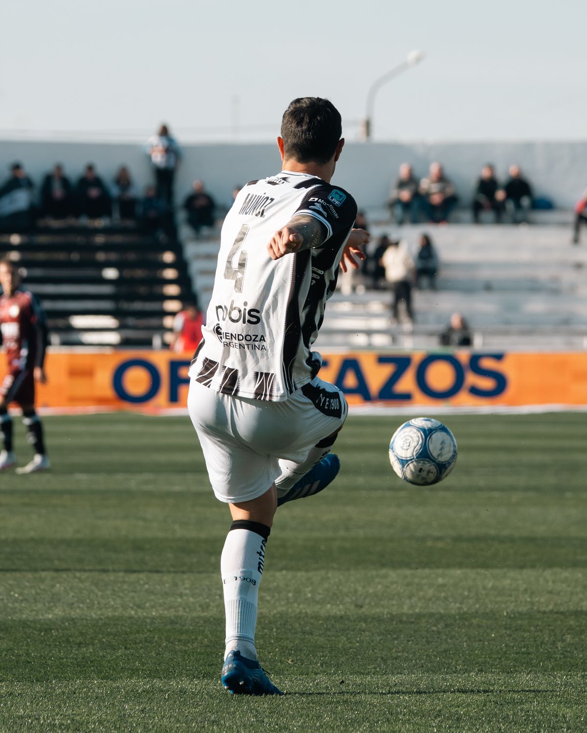 A footballer in action striking the ball during a match on a pitch