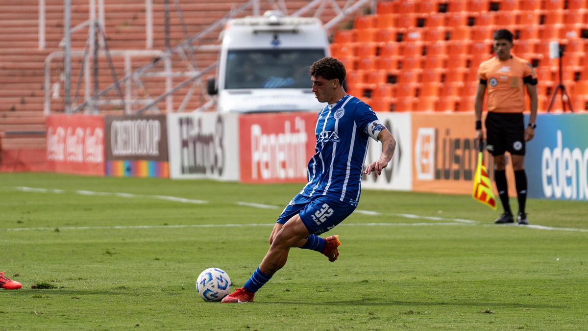Footballer striking the ball on a floodlit pitch during an evening match