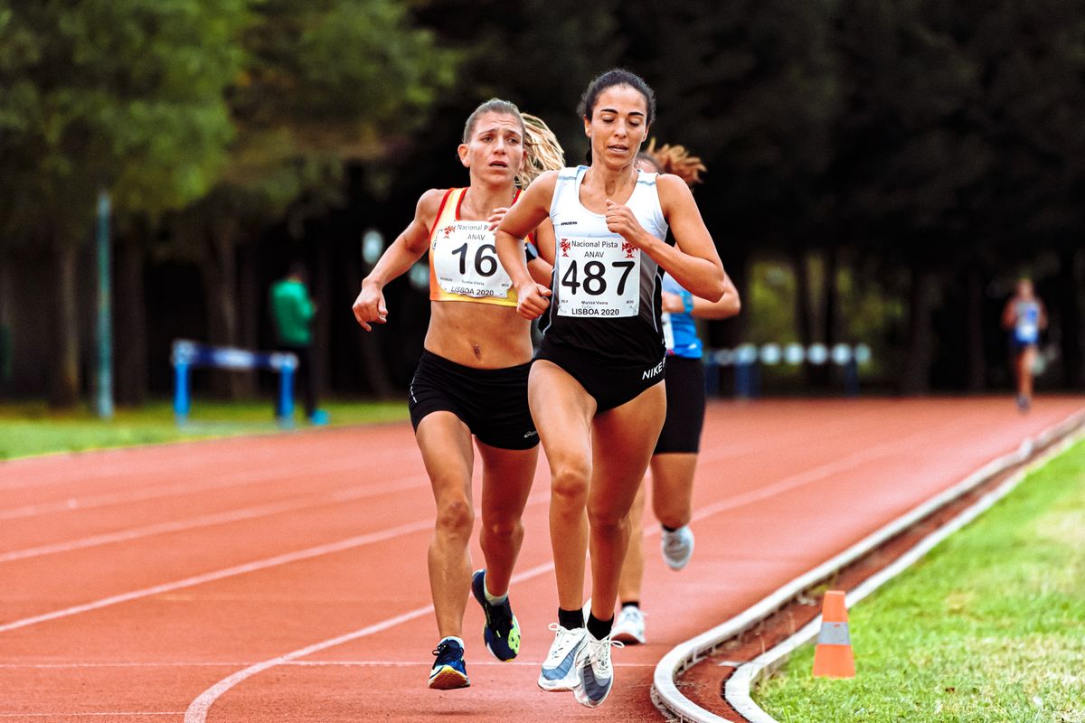 Two distance runners racing side by side on an athletics track during a road race