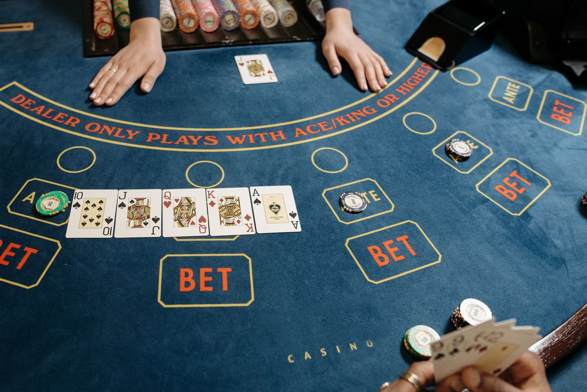 A baccarat table with a dealer dealing cards and chips on the felt