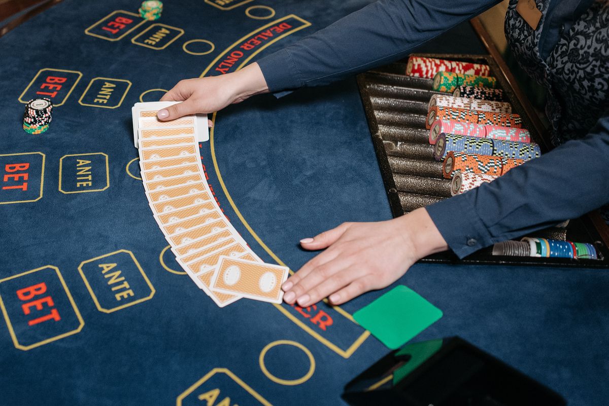 Dealer's hands spreading a deck of cards across a blue felt casino table