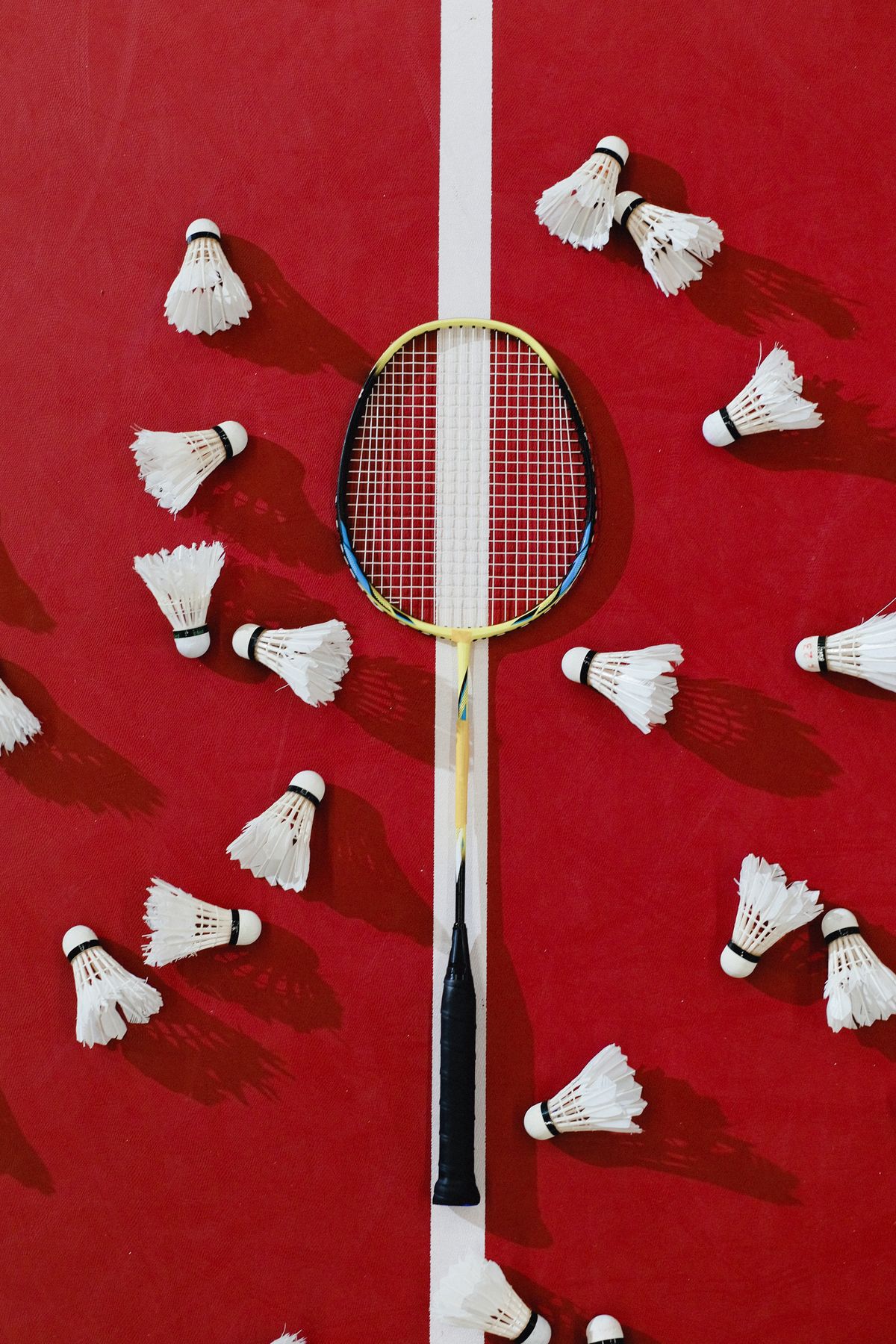 Badminton racket and shuttlecocks resting on a red badminton court