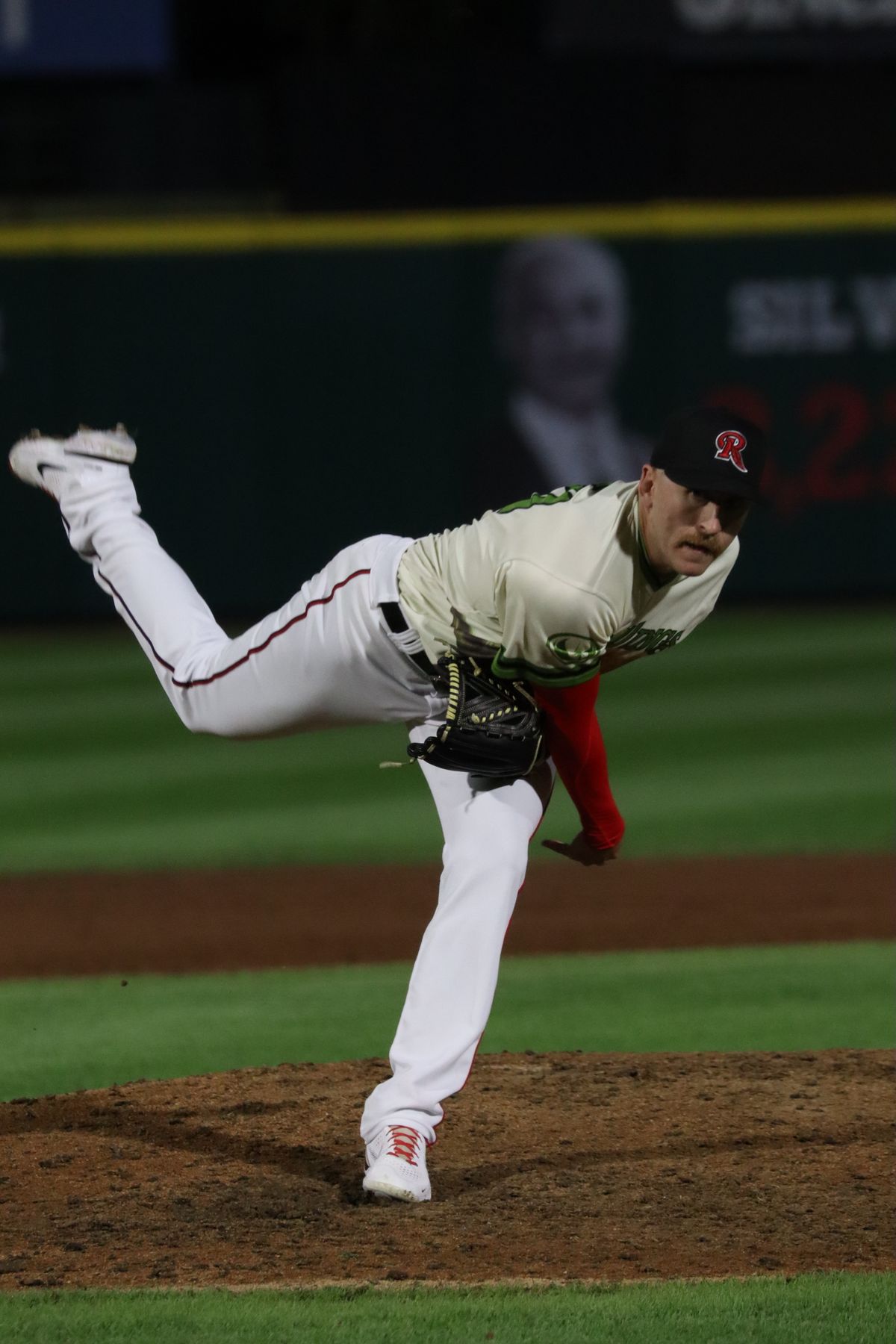 Baseball pitcher throwing a pitch from the mound during a night game