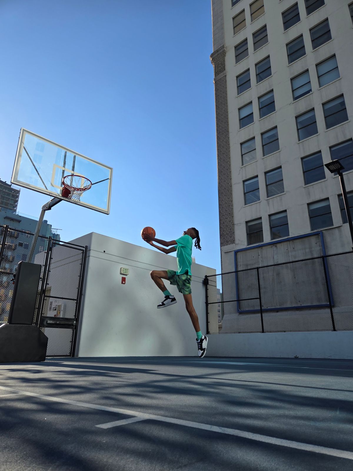 A young basketball player performing a slam dunk on an outdoor court