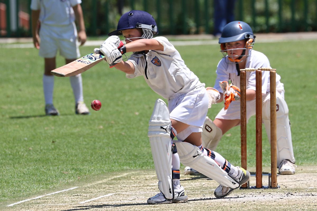 Cricket match in progress with batsman playing a shot on green field