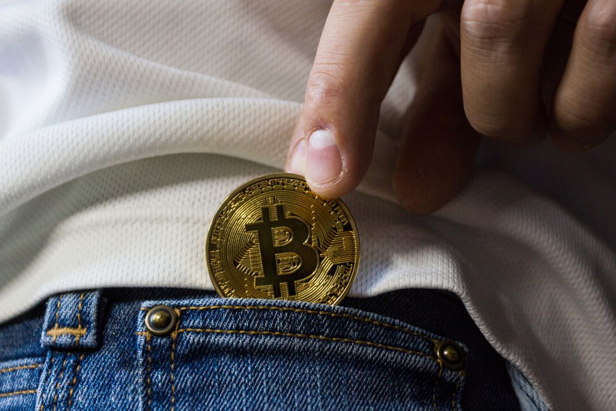 Gold Bitcoin coins placed on a dark reflective surface with blue lighting