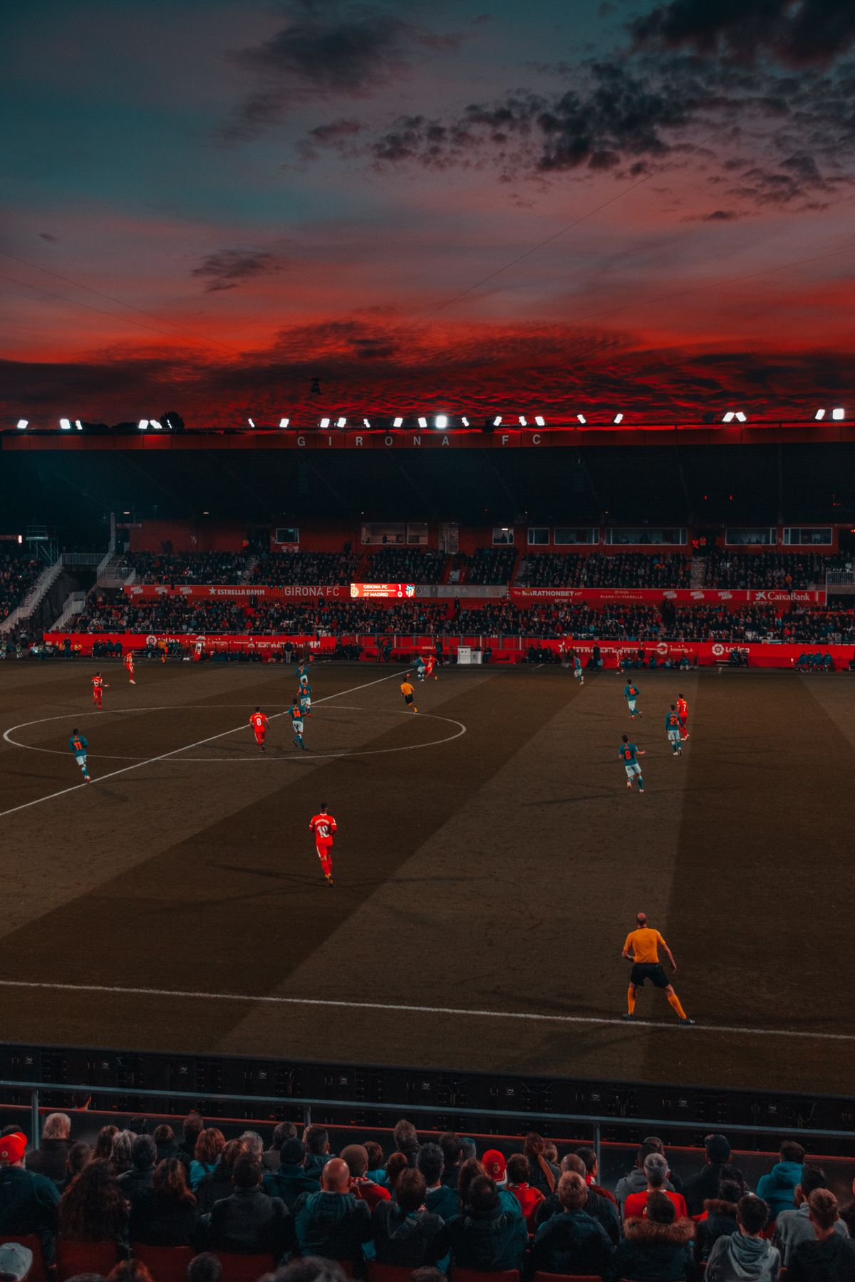 Football match at a Spanish stadium under a dramatic red sunset sky