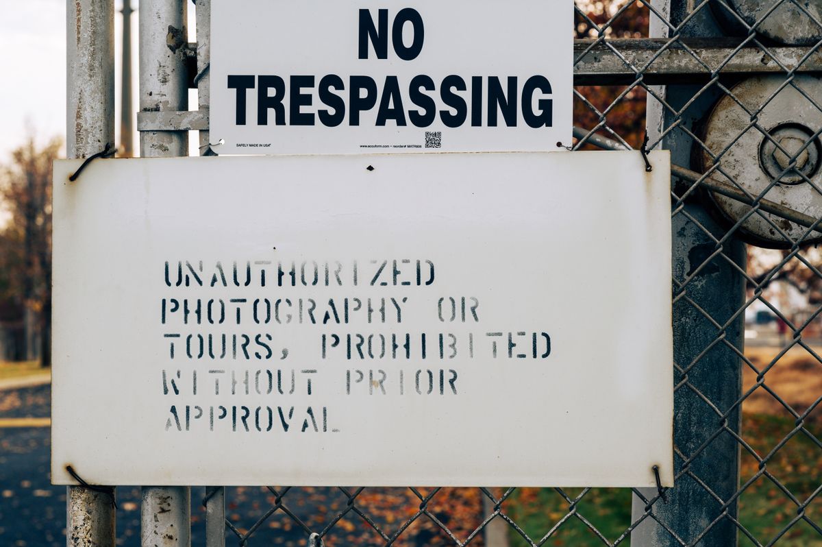 Warning sign on a chain-link fence prohibiting unauthorized access
