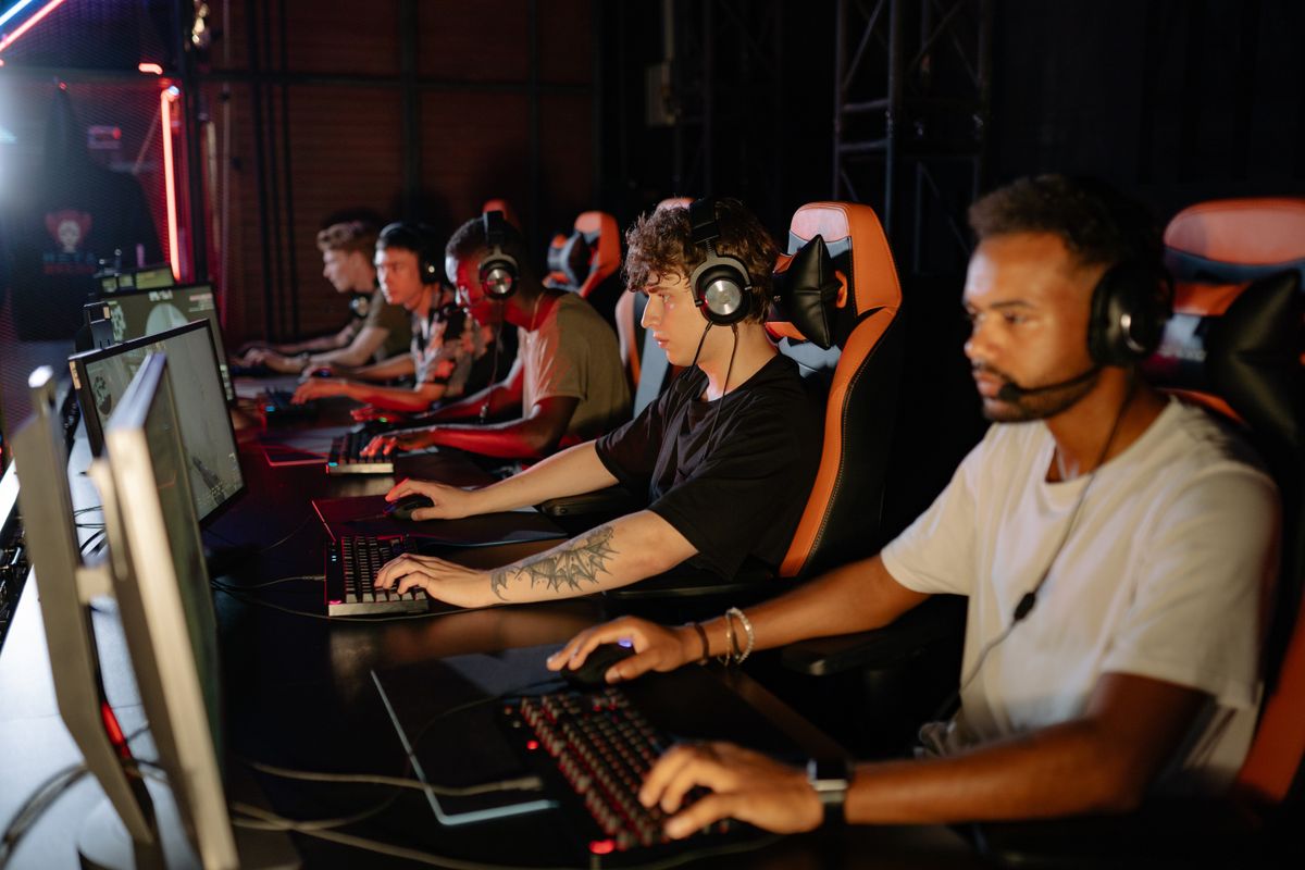 Esports competitors wearing headsets at a tournament venue with red stage lighting