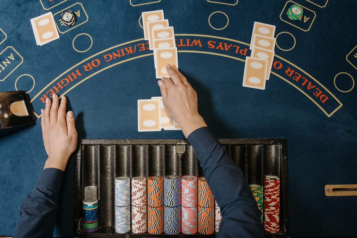 Dealer distributing cards at a casino blackjack table with chips in view