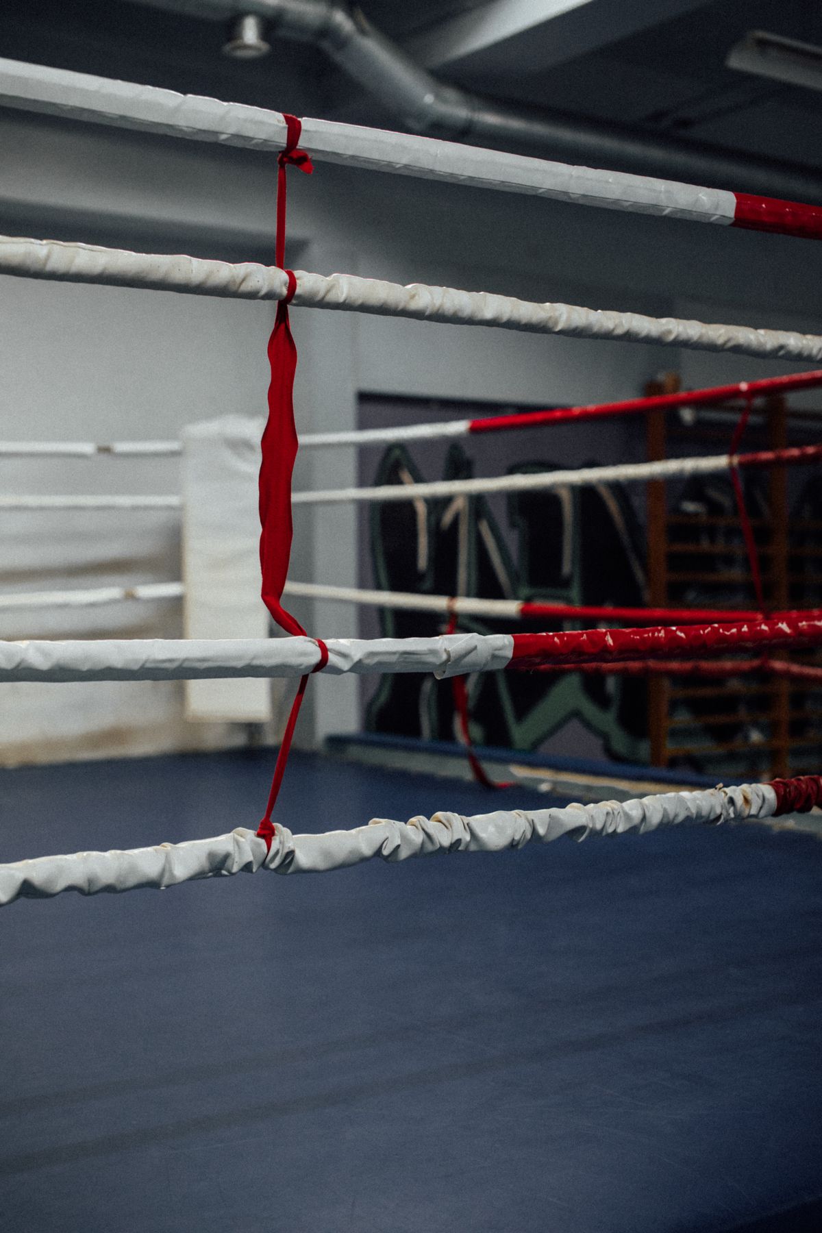 Corner of a boxing ring with white padded ropes secured with red tape
