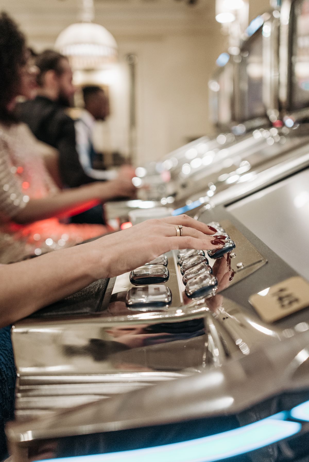 Hand pressing the spin button on a slot machine in a casino