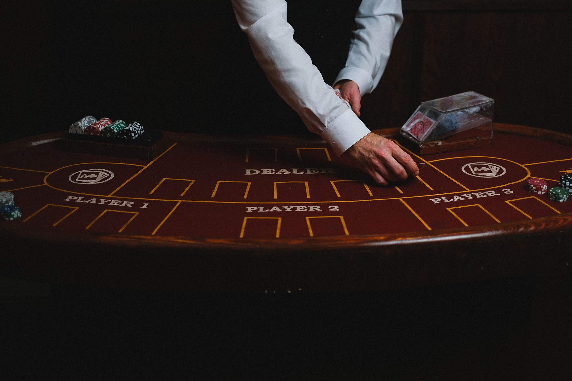A croupier deals cards on a dimly lit casino table, showcasing gambling atmosphere
