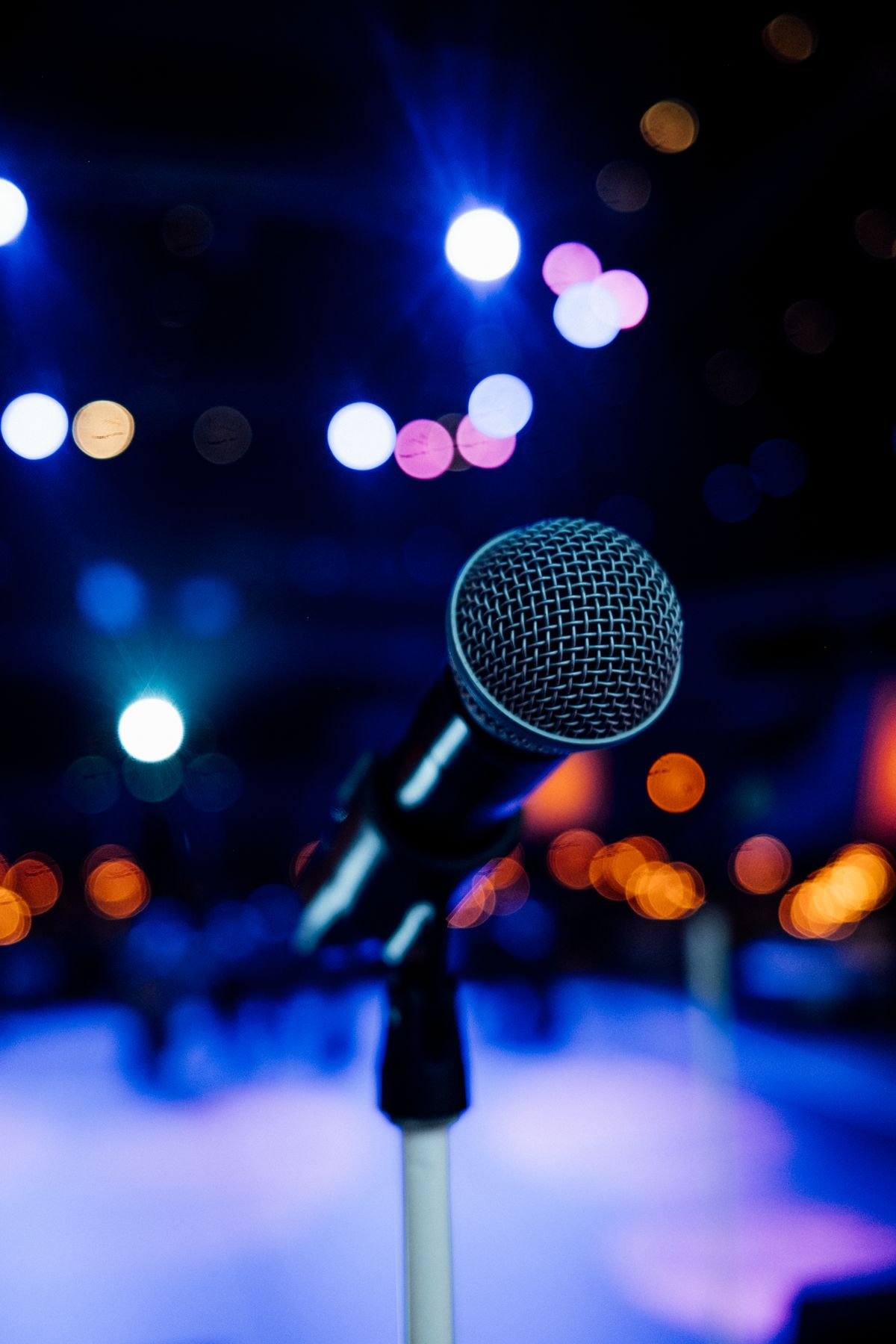 Studio microphone on a stage lit with blue and orange bokeh lights