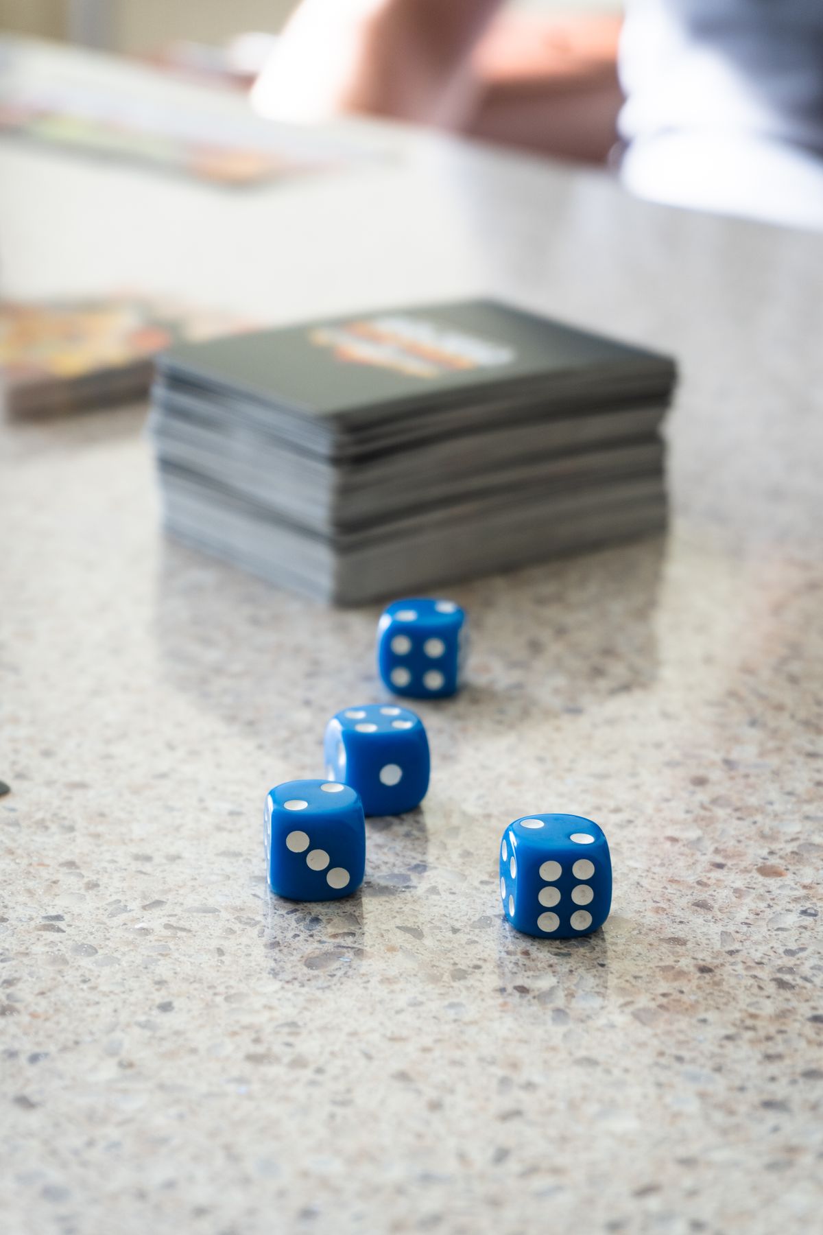 Blue dice with white pips scattered near a stack of dark playing cards