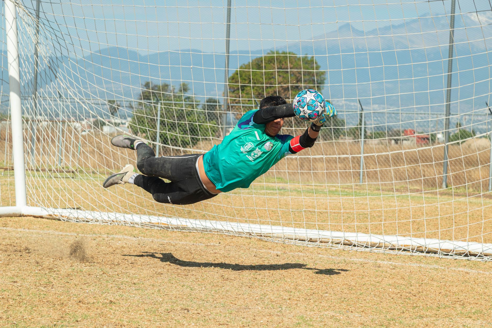 Dynamic action shot of a soccer goalkeeper making a diving save during a match in Puebla, México