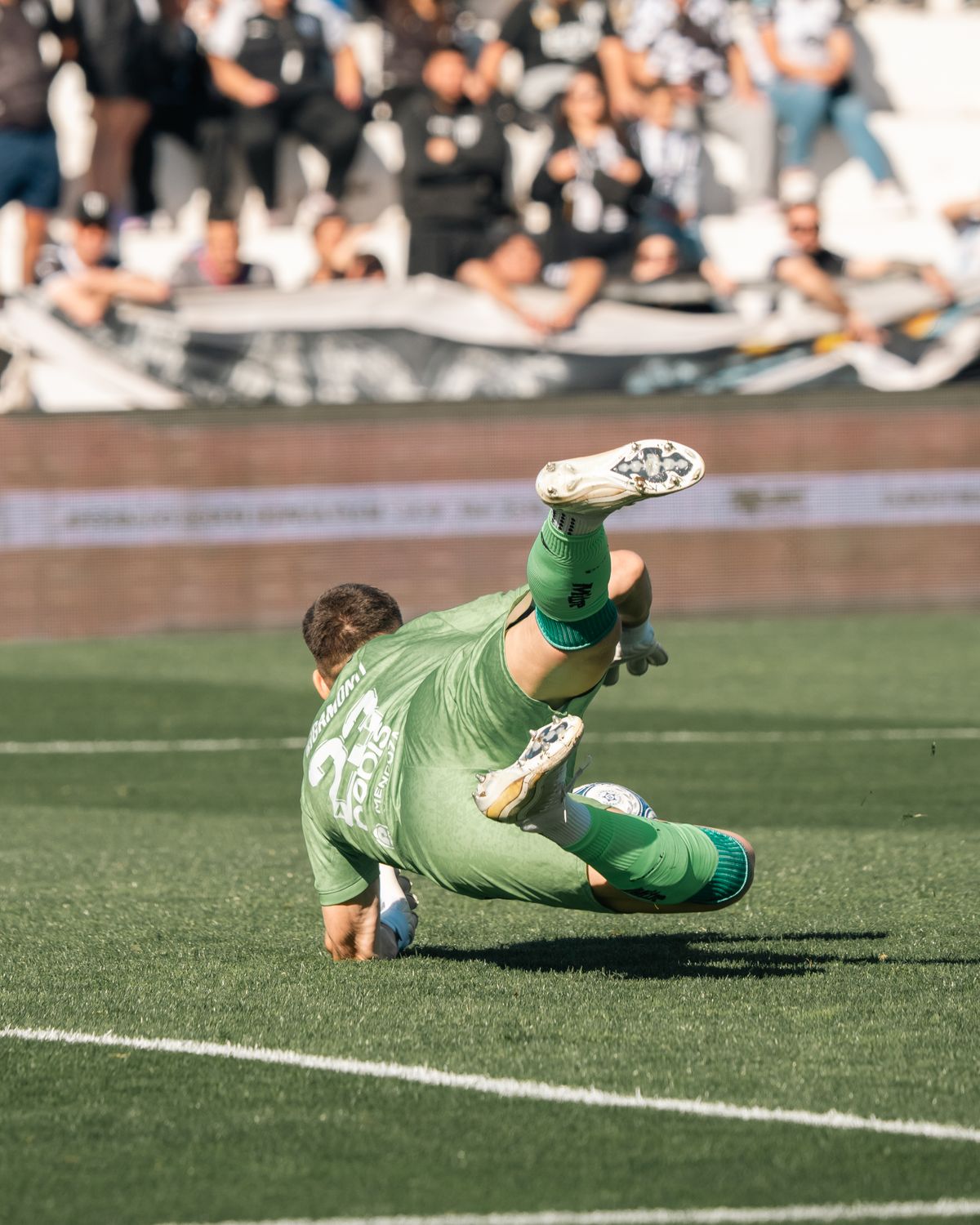 A goalkeeper diving to make a save in front of the goal