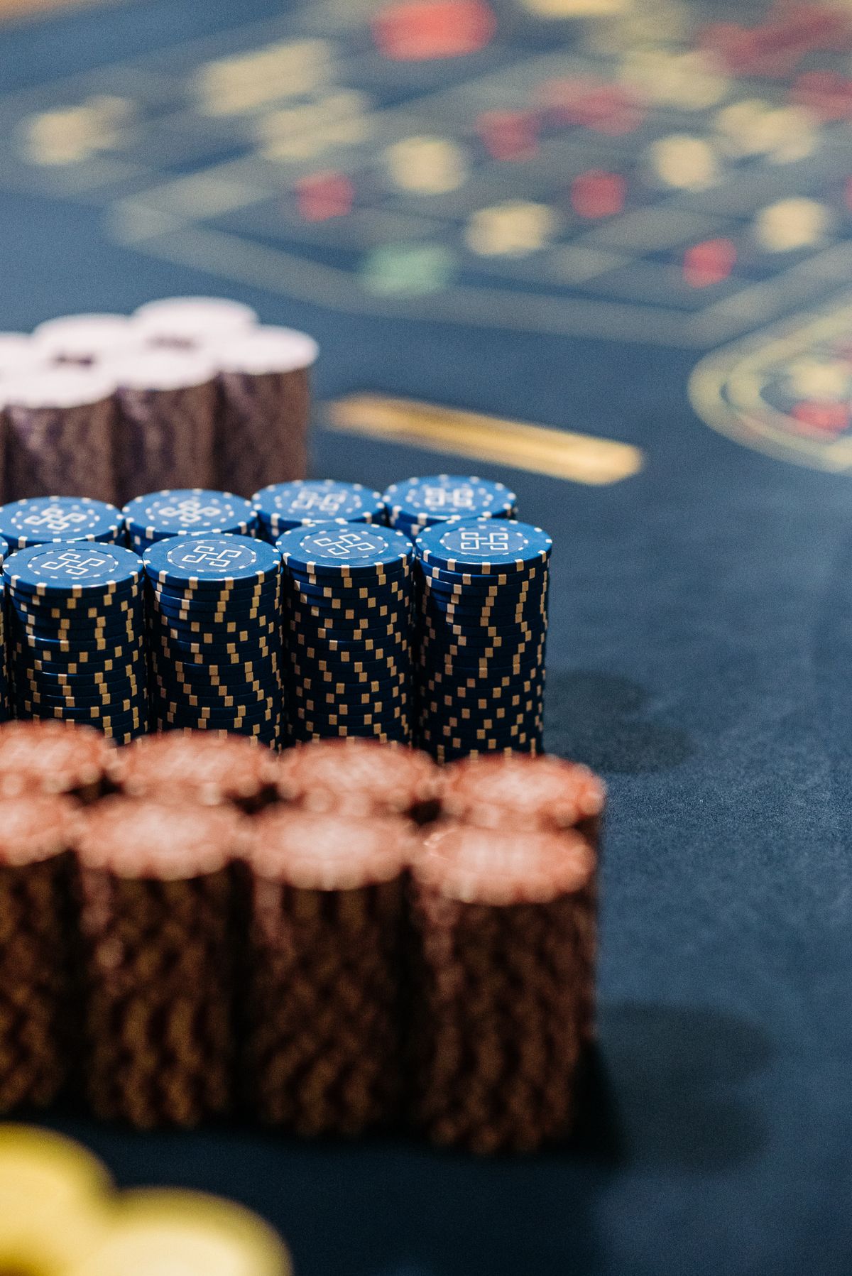 Stacks of blue, brown and white poker chips on a green felt casino table