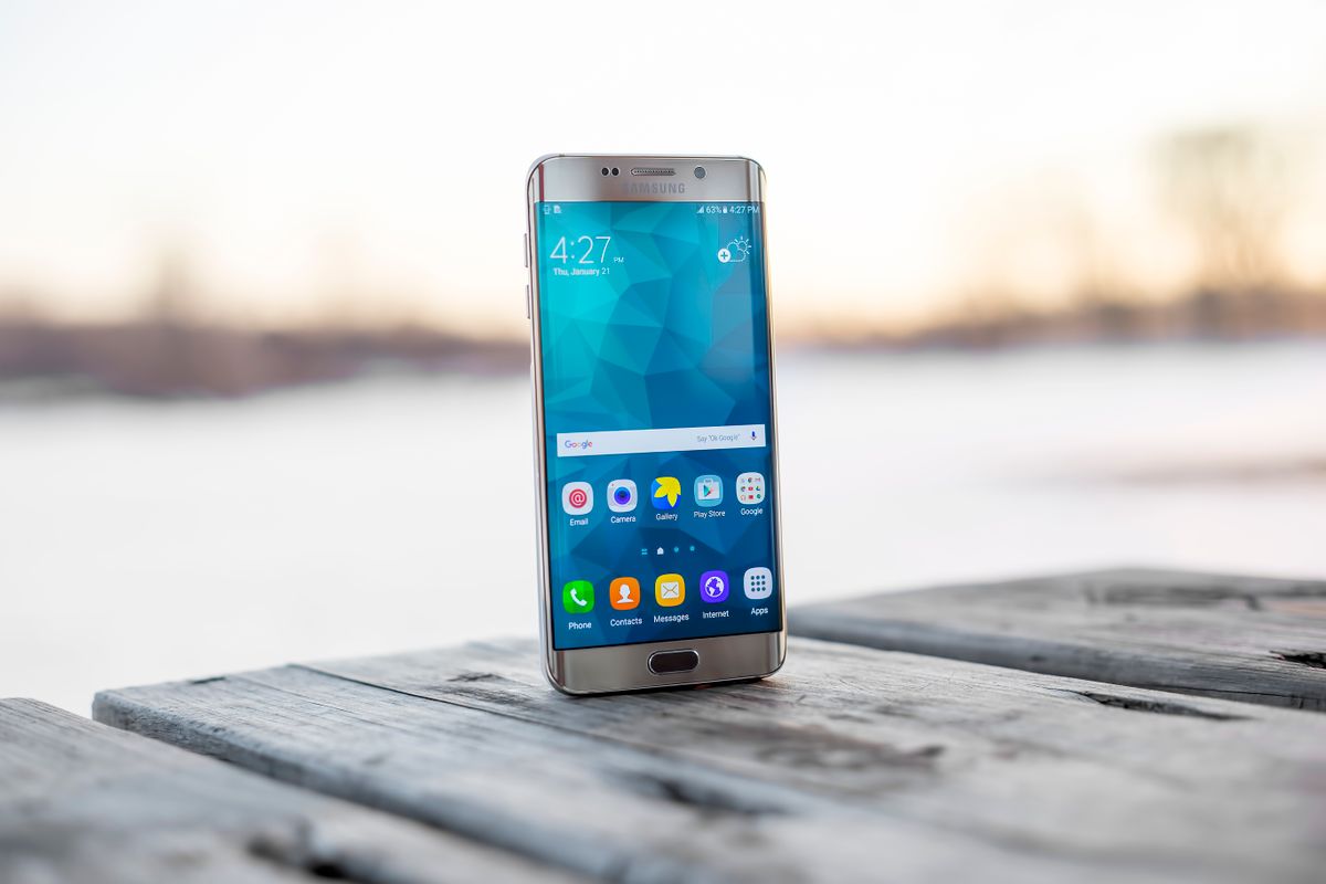 Smartphone standing upright on a wooden surface, ready for mobile gaming