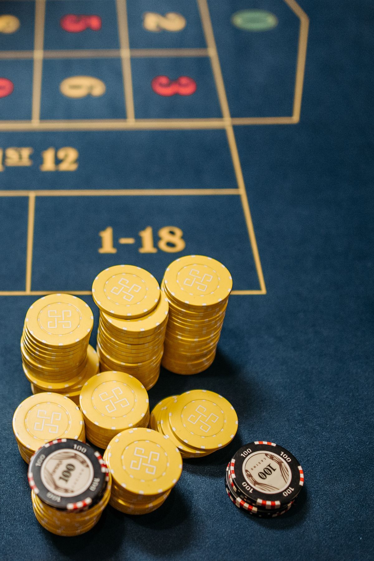 Gold cryptocurrency tokens stacked with casino chips on a roulette table layout