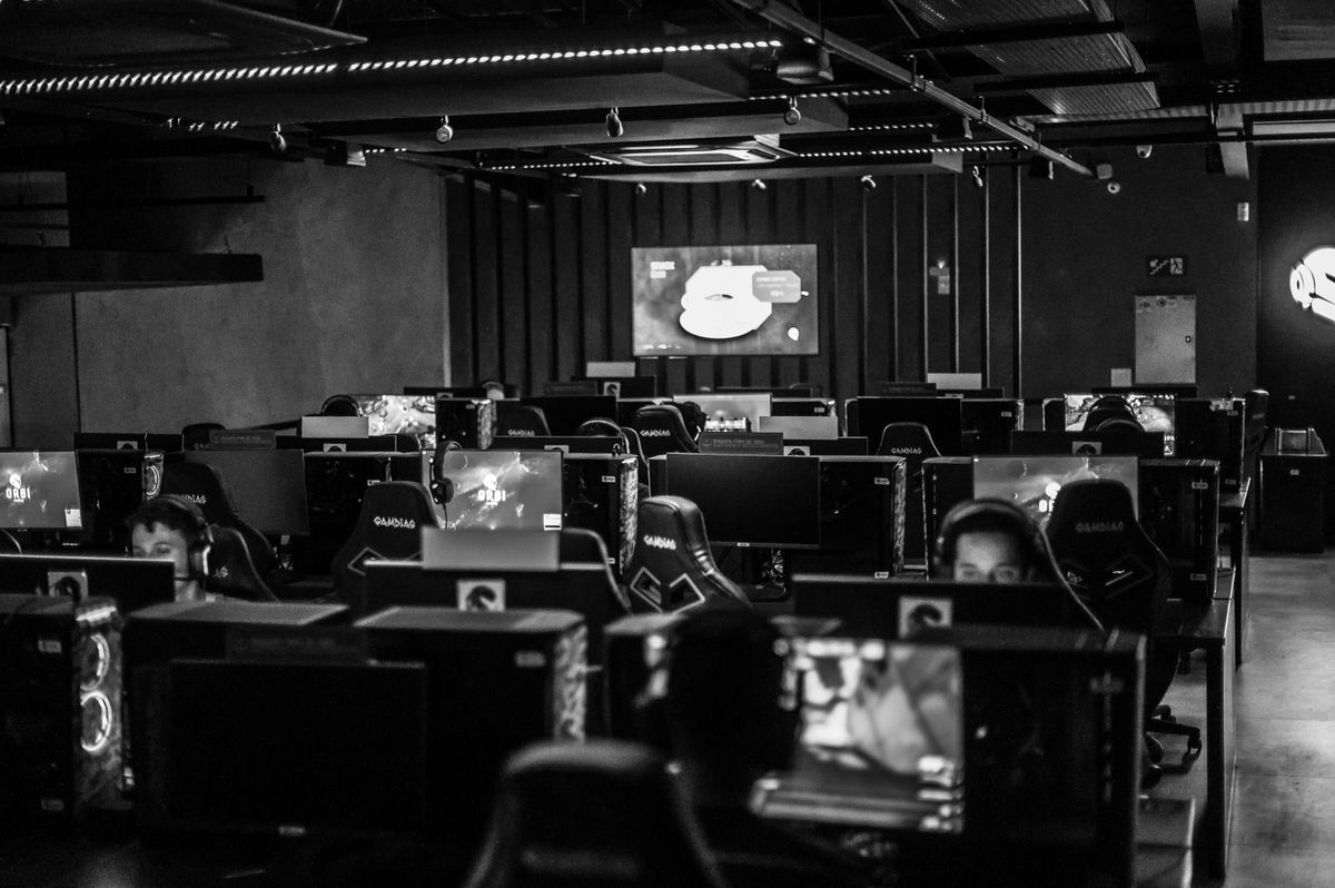 A row of esports competitors at gaming desks under blue and purple stage lighting