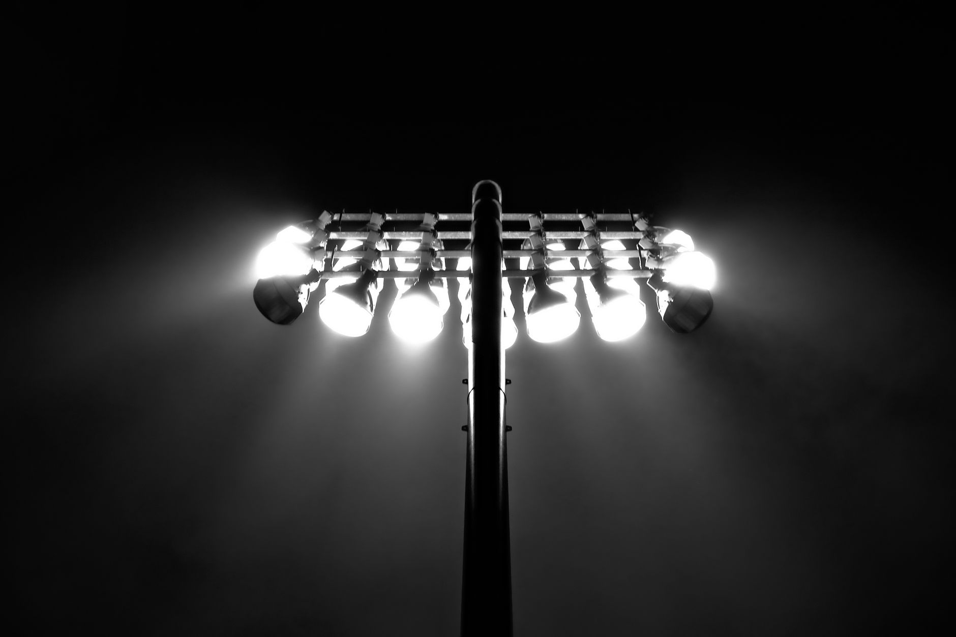 Black and white photo of stadium floodlights illuminating the night sky in Boston