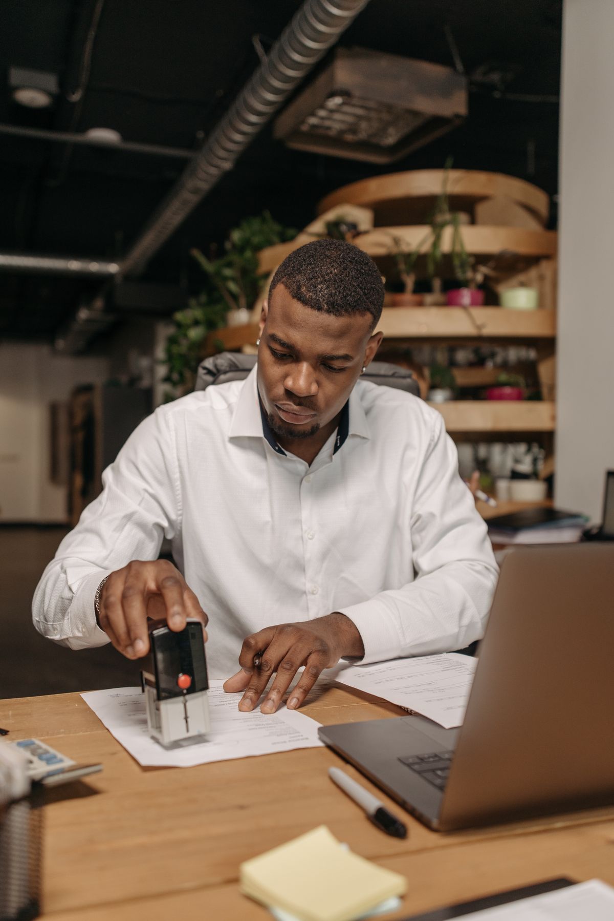Person stamping a document at an office desk with a laptop nearby