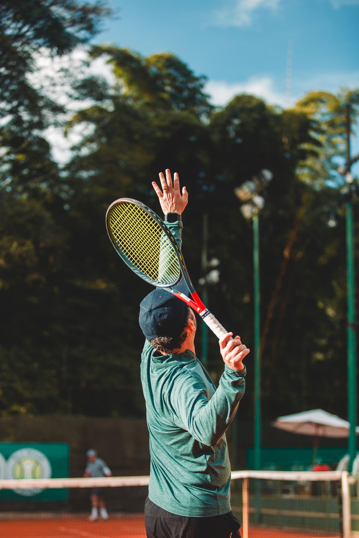 Tennis player serving during a match on an outdoor court