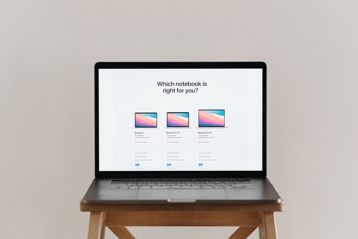 Laptop on a wooden stool displaying a comparison of three product models