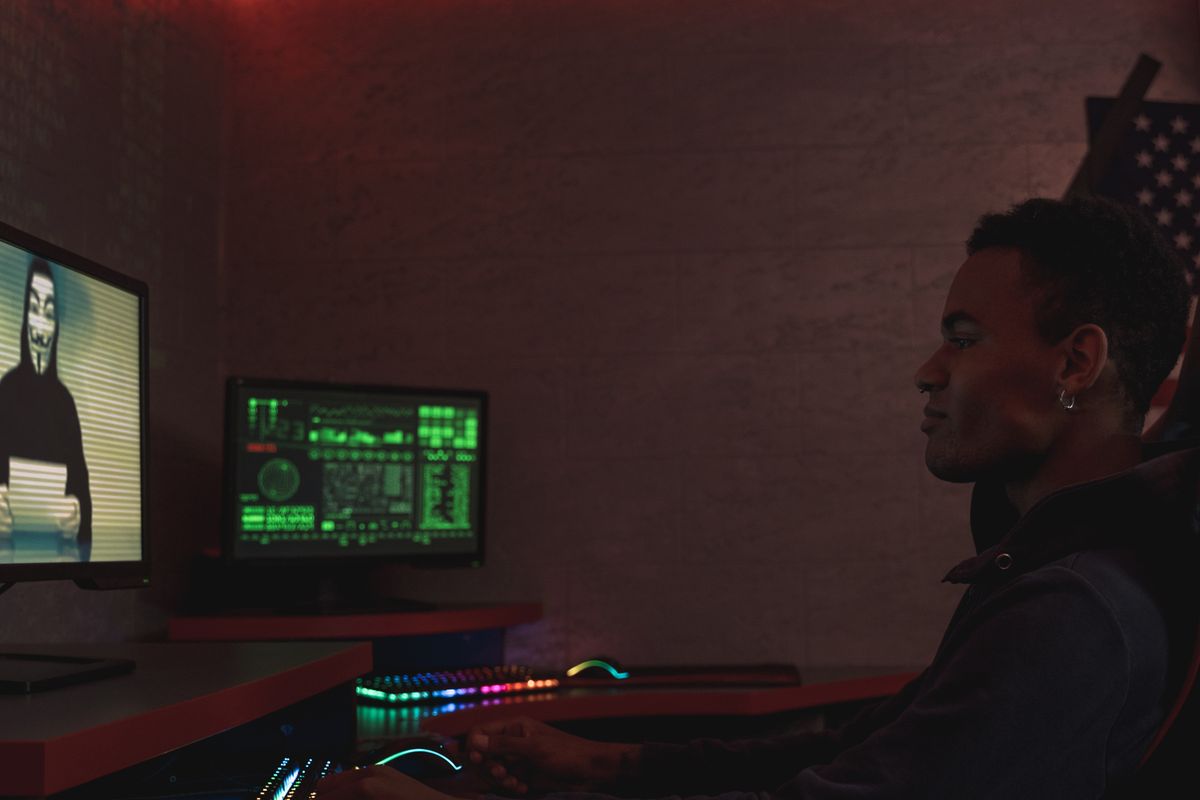 Person at a desk monitoring multiple screens showing data feeds in a dark room