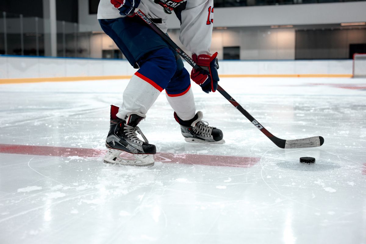 Ice hockey player handling the puck with a stick on a rink