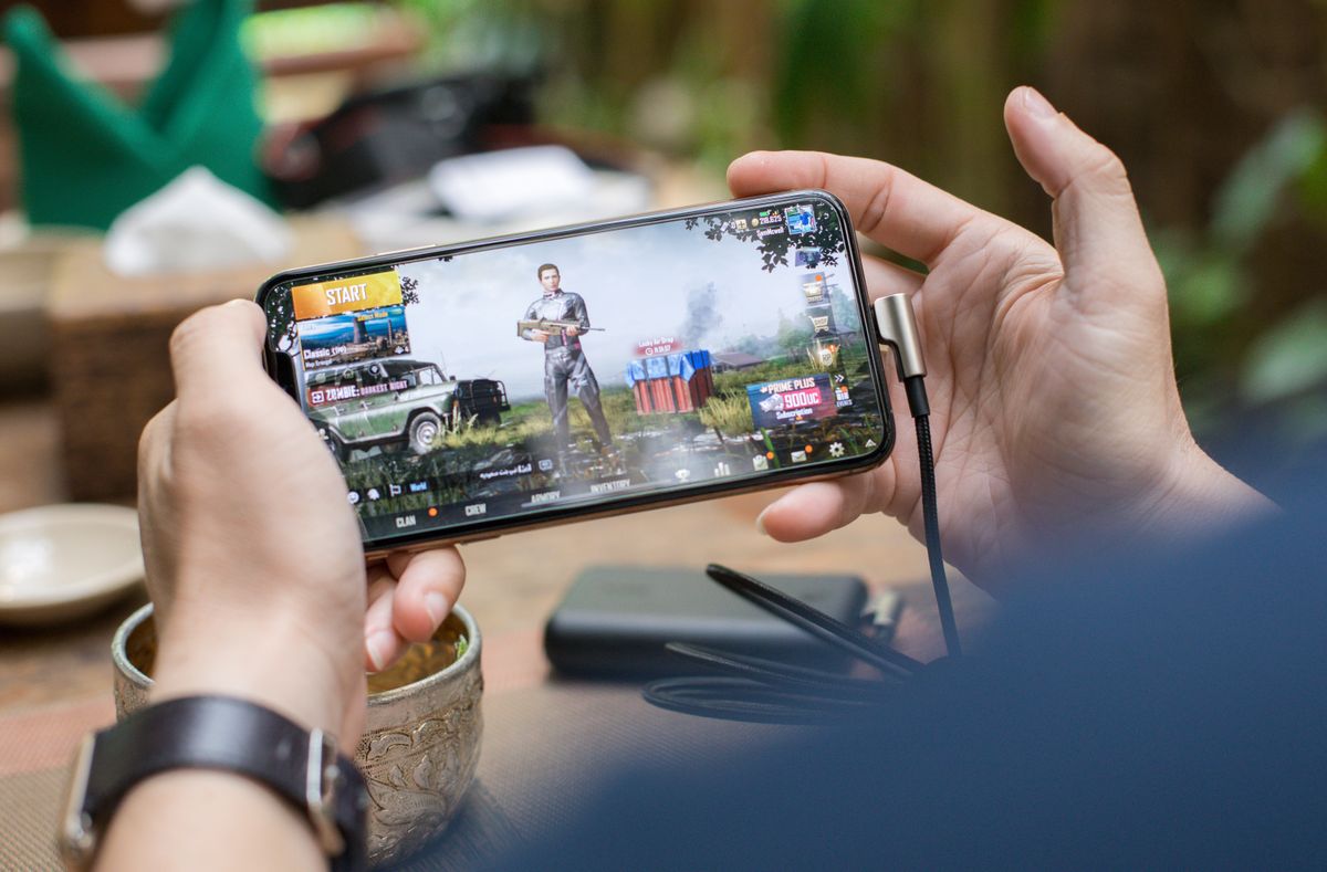 Hands holding a smartphone in landscape orientation during mobile gaming
