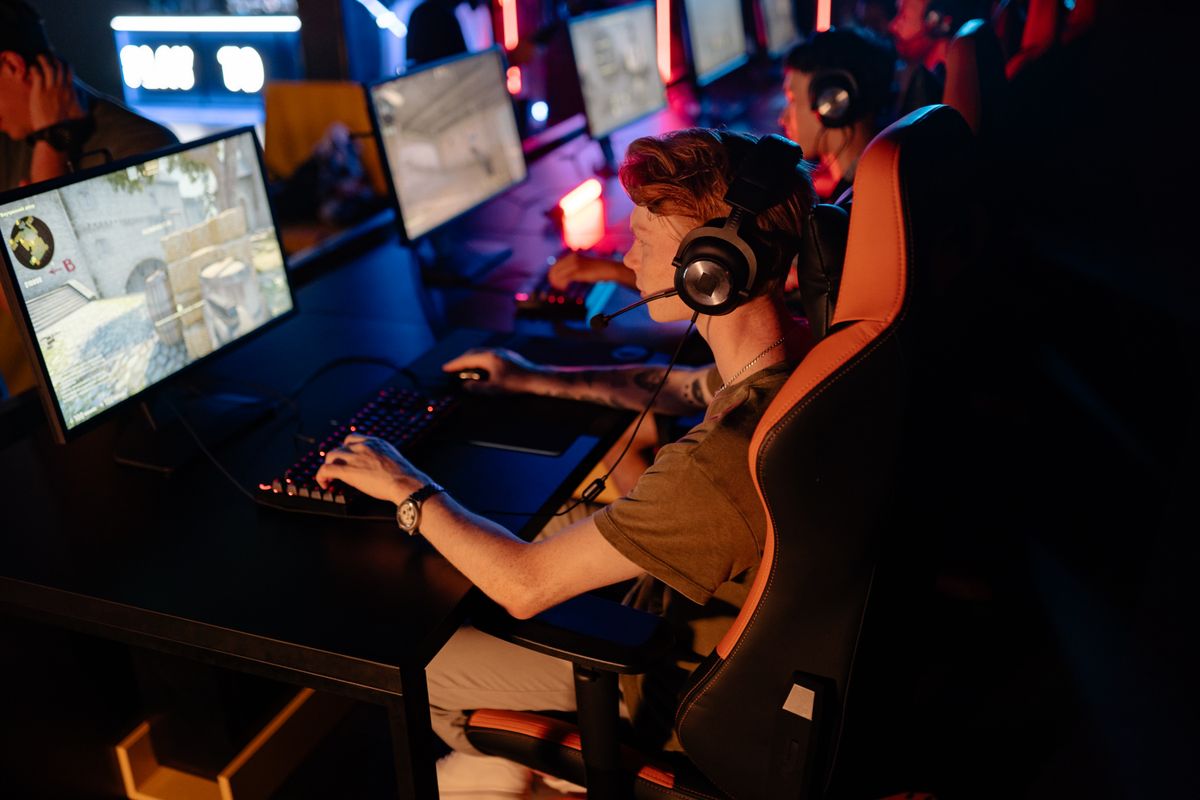 Young man with headphones focused on a computer screen in a dimly lit room