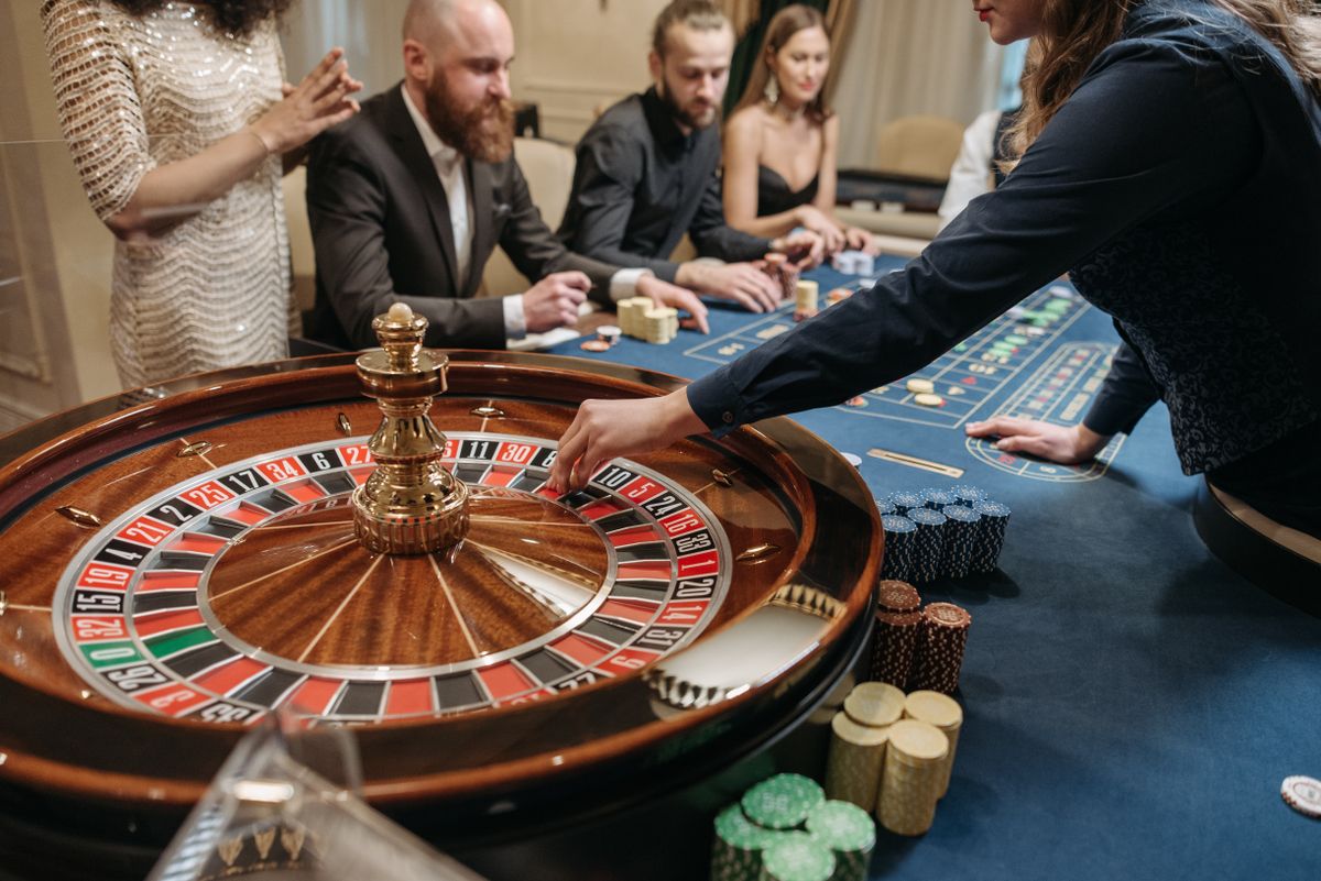 A dealer spinning a roulette wheel while players sit around the live table