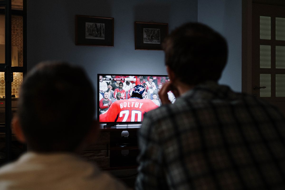 Two people watching a hockey match on a television in a living room