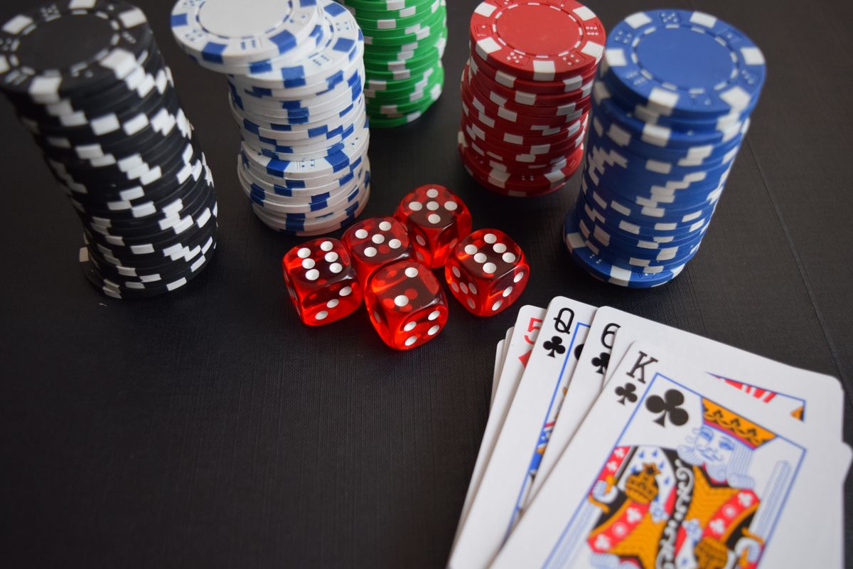 Poker chips, red dice and playing cards arranged on a dark surface