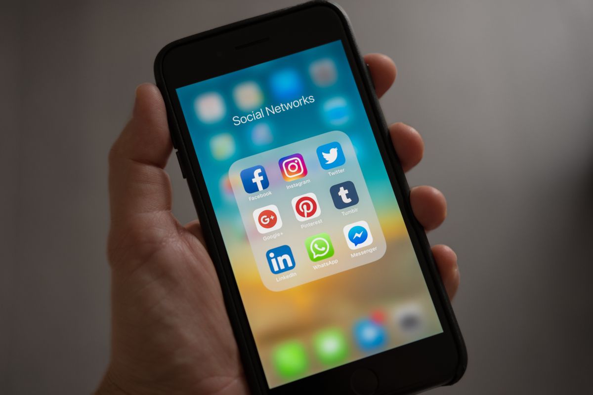A hand holding a smartphone showing a grid of app icons on the home screen