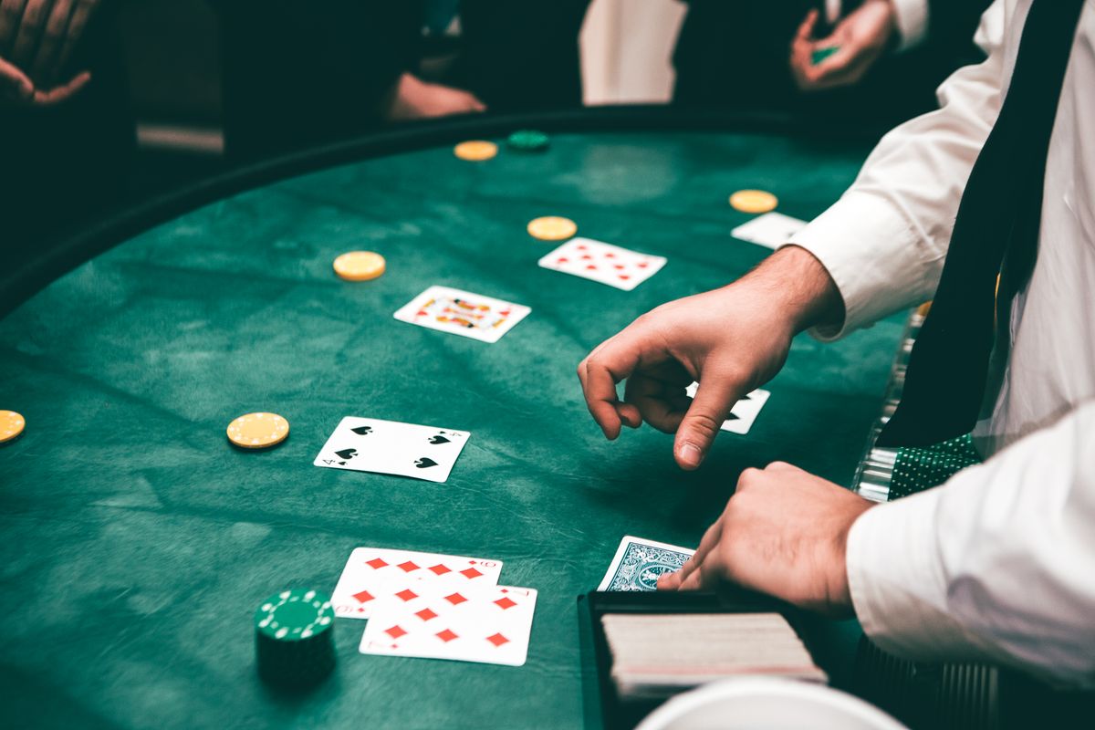 Casino dealer managing a poker hand on a green felt table