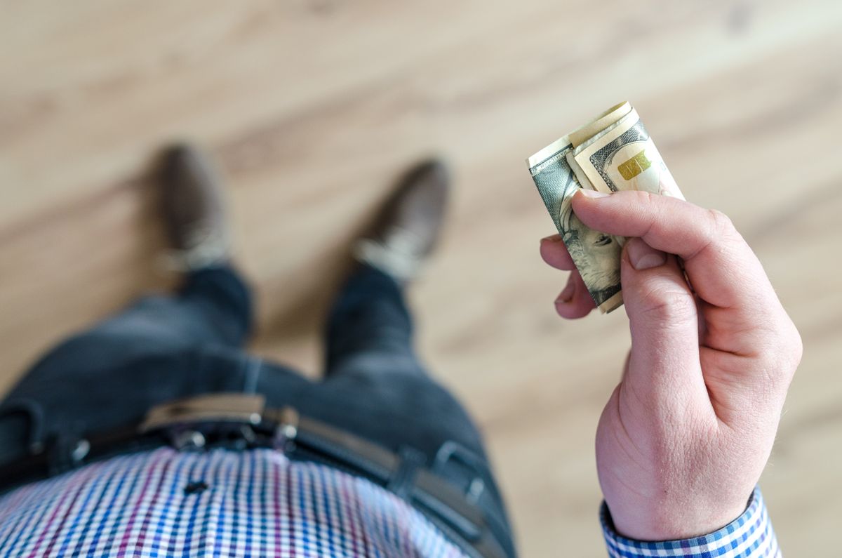 Hand holding a folded stack of US dollar bills
