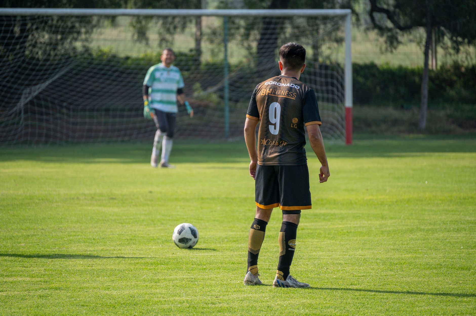 Soccer player in action preparing for a penalty kick on a sunny day in a green field
