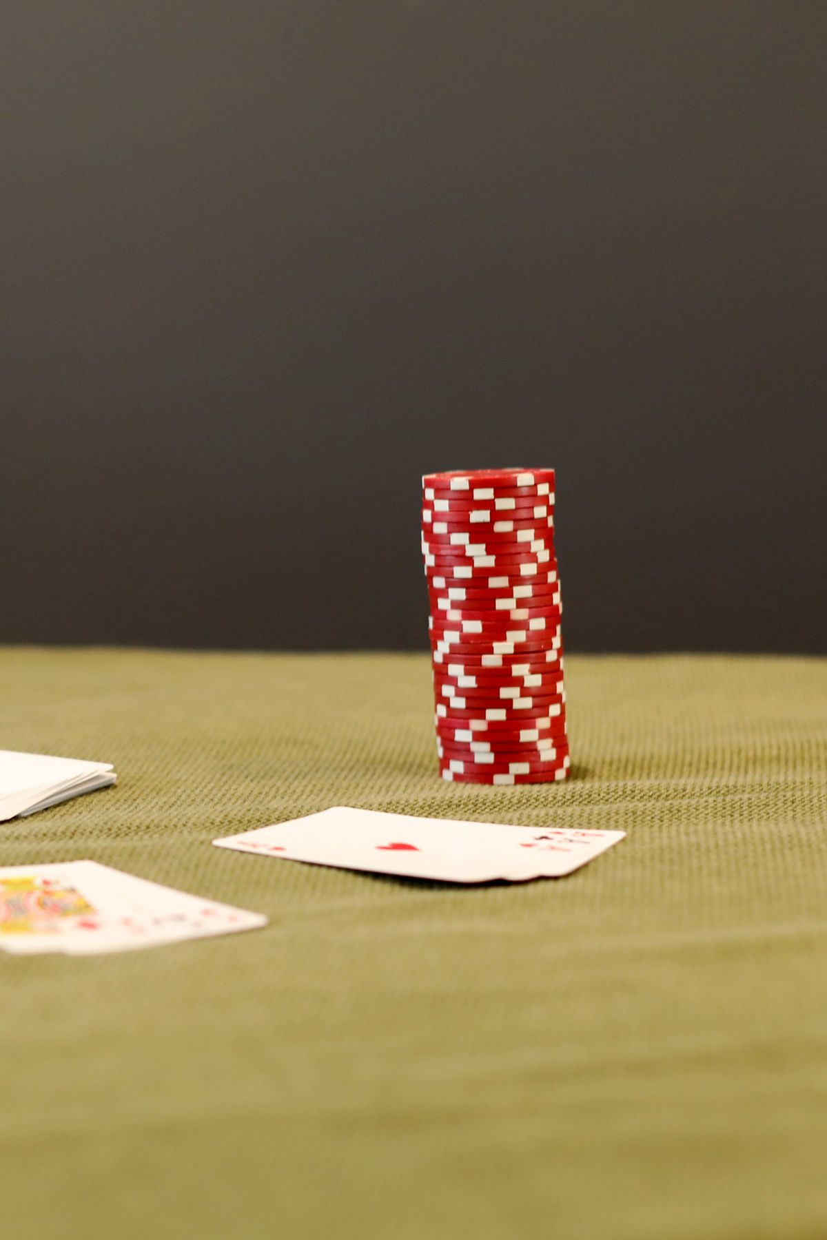 Playing cards fanned out on a green felt table beside poker chips