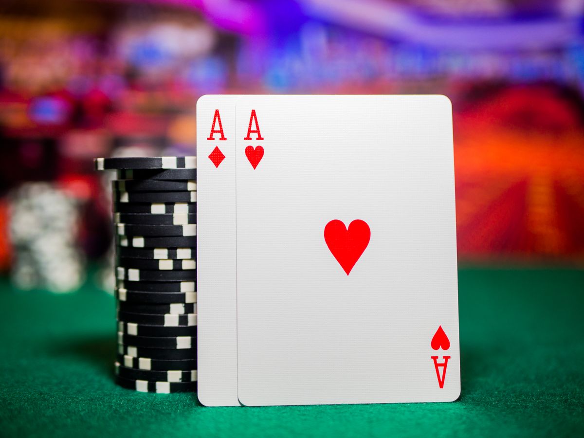 A pair of aces and stacked poker chips on a green felt table