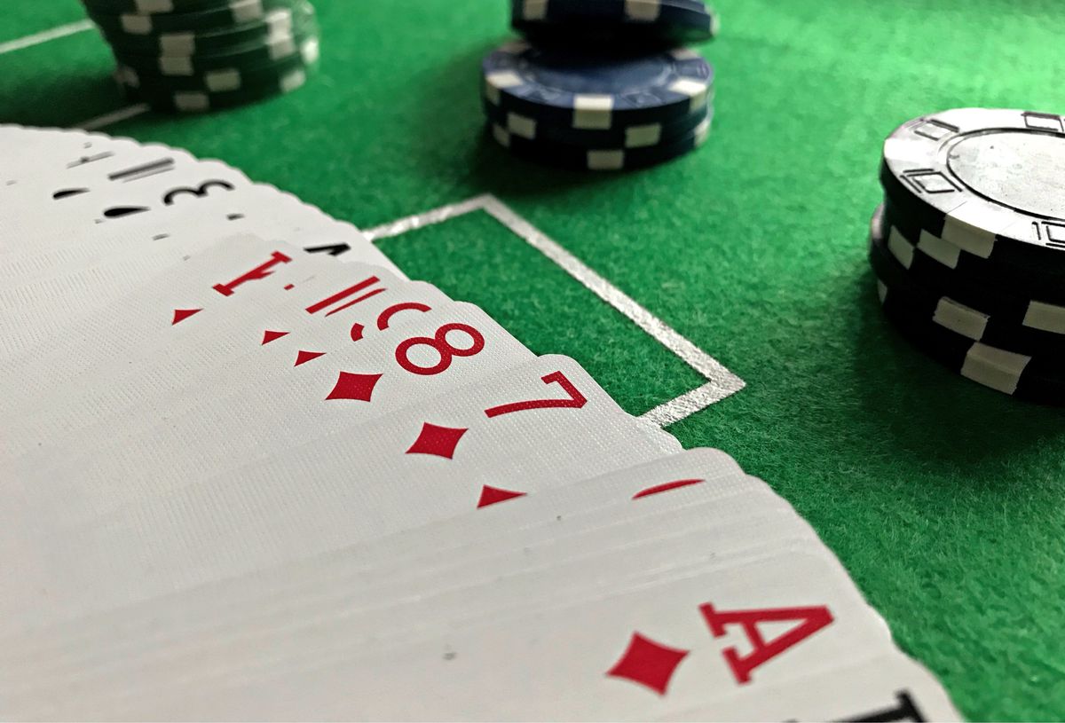 Playing cards fanned out on a table beside stacked poker chips