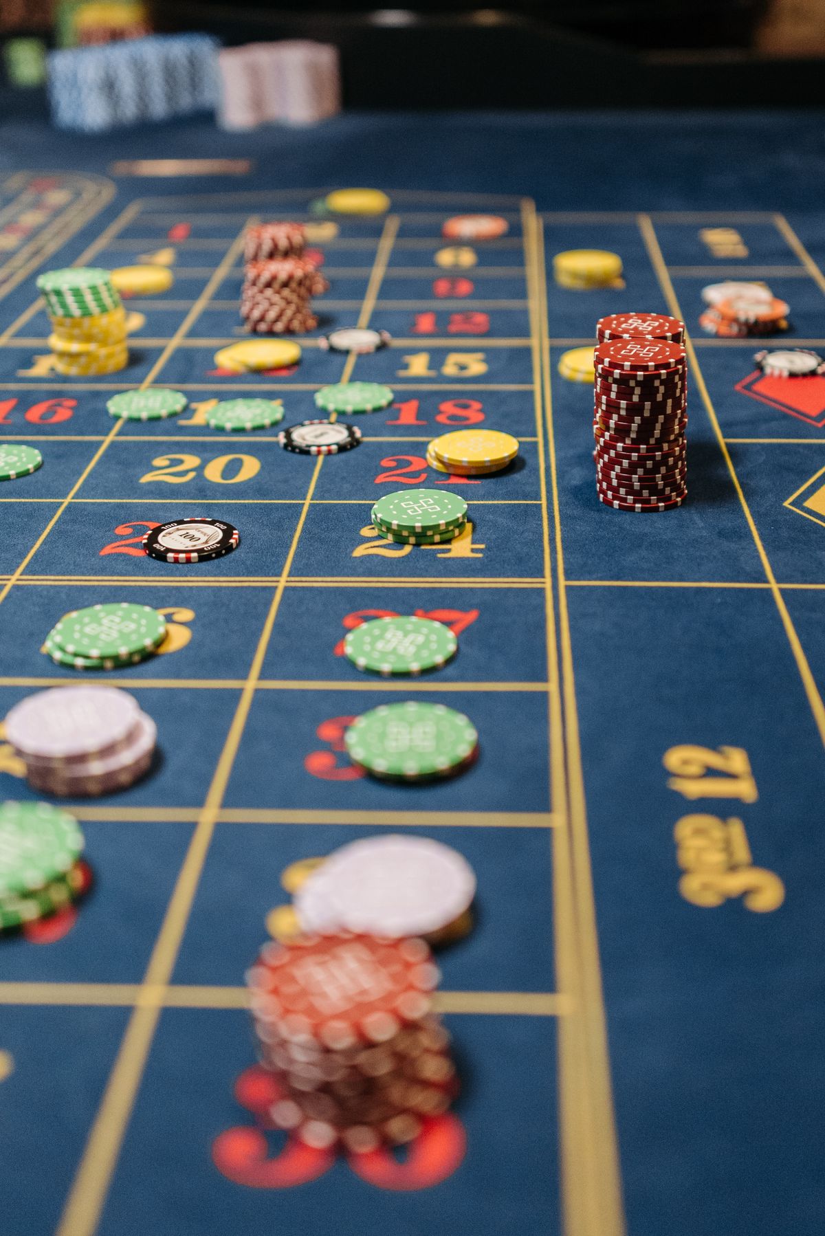 Blue felt roulette table covered with stacks of colorful casino chips