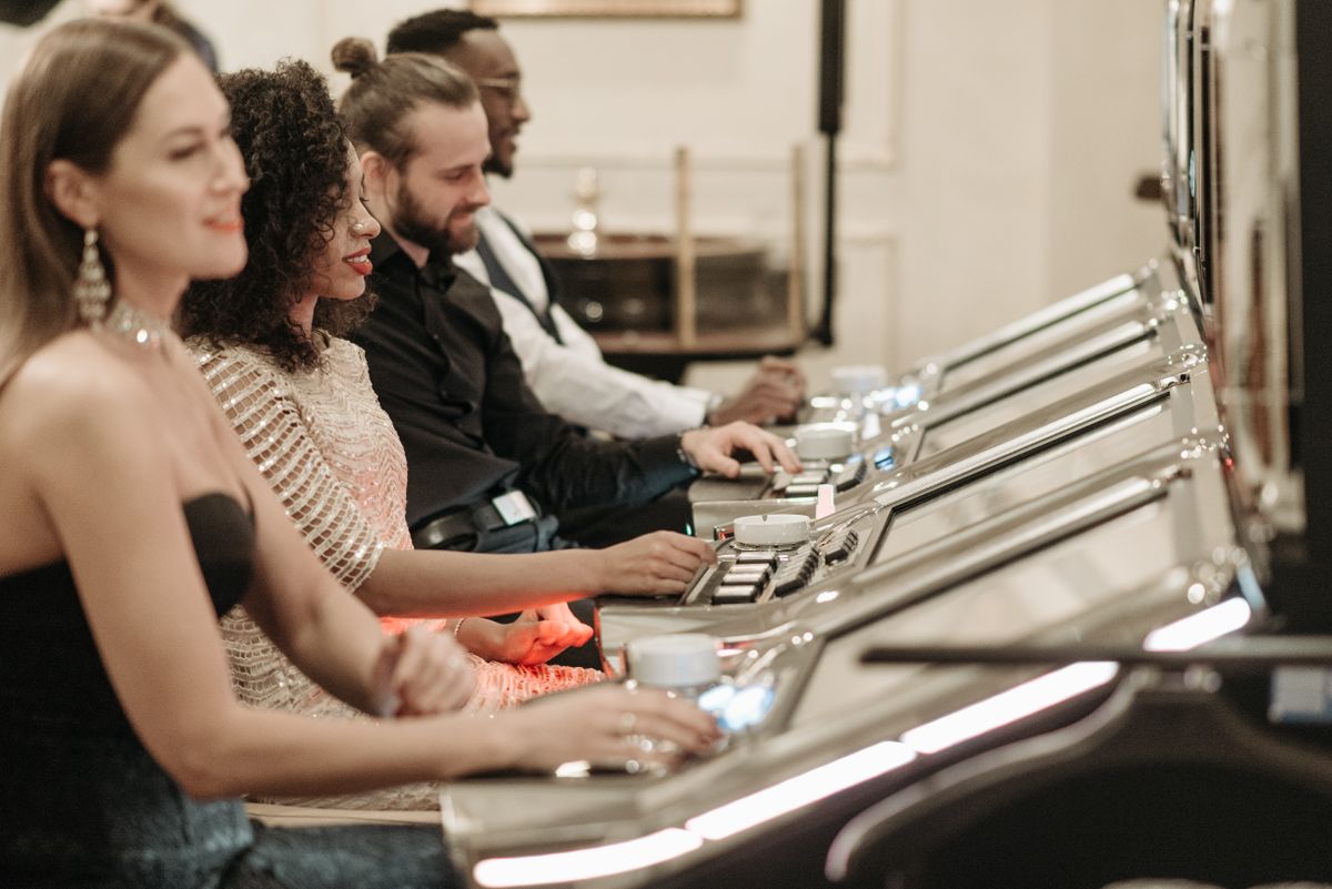 A group of adults sitting at slot machines in a casino playing together