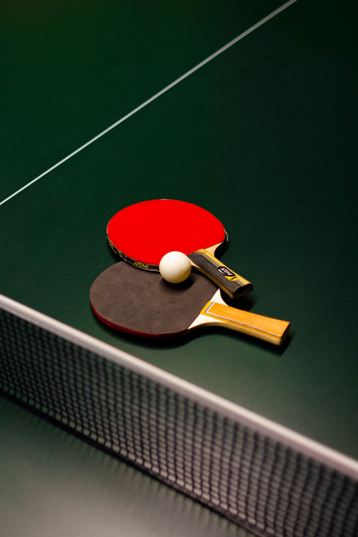 Table tennis ball and paddle on a green table surface