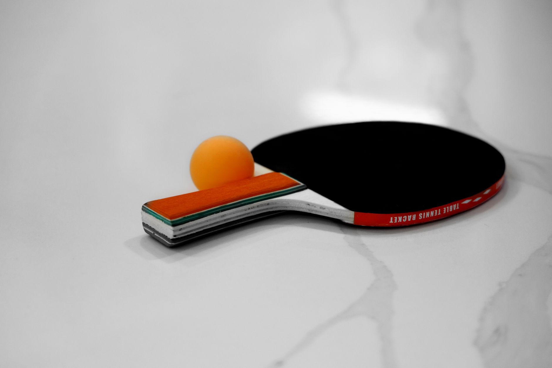 Close-up of a table tennis racket and orange ball on a white background