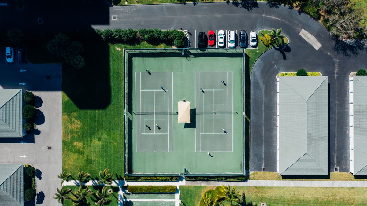 Aerial view of a green tennis court with players during a match